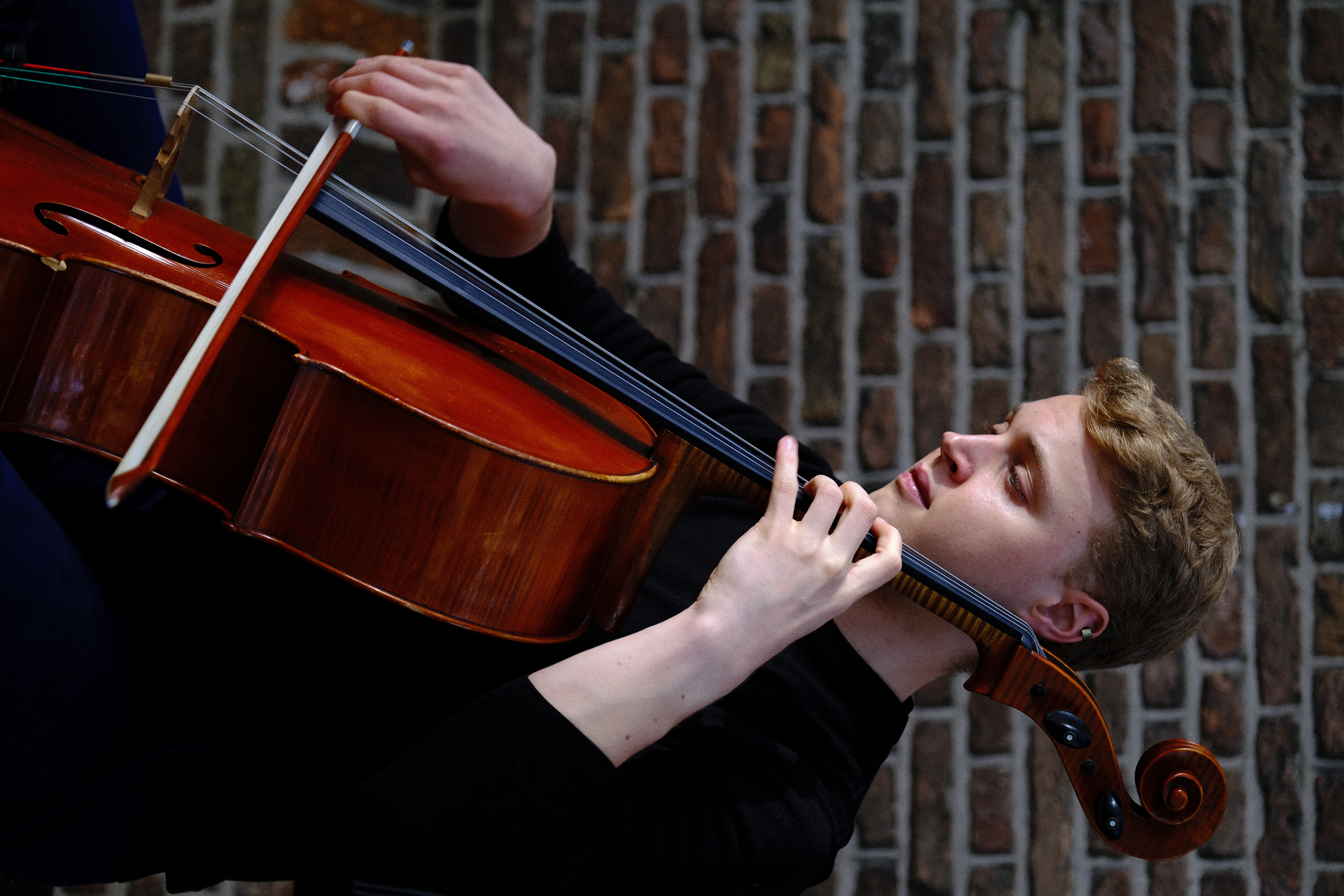 Close-up of Luka Stefanović – expressive gaze and polished cello wood, The Hague 2023